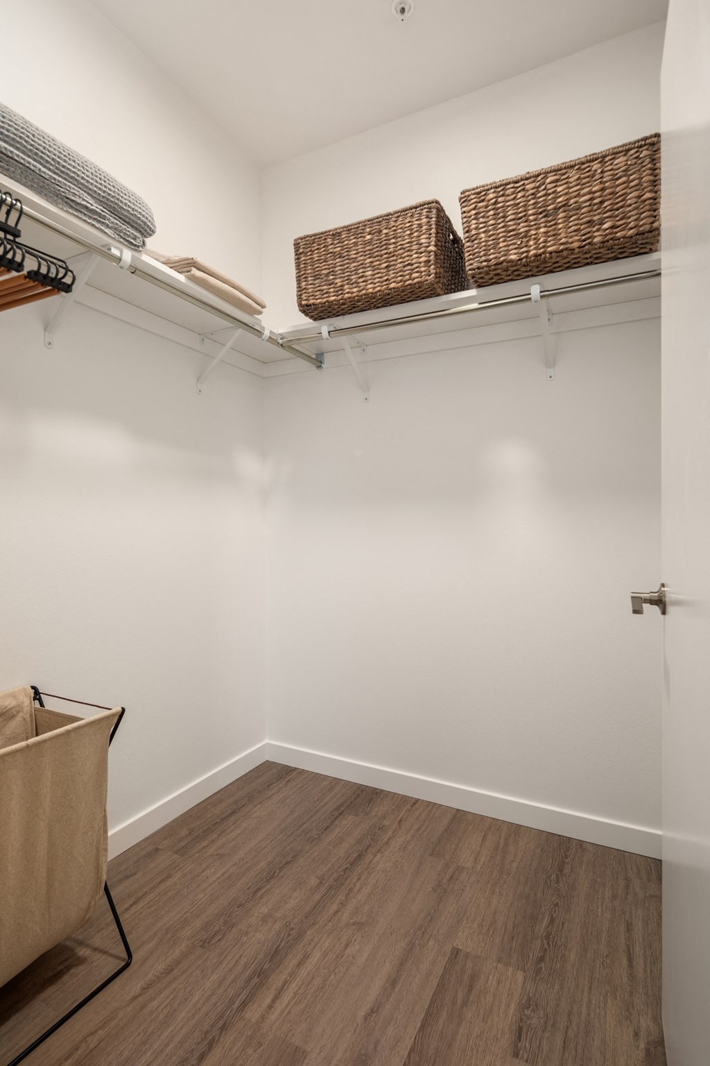 a walk in closet with wicker baskets on the shelves and a door to a