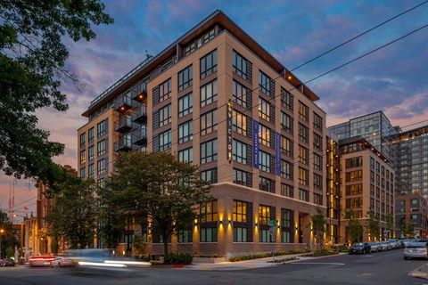 a rendering of a building on a city street at dusk