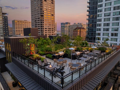 a rooftop terrace with tables and chairs and buildings in the background