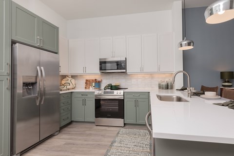 A kitchen with a stainless steel refrigerator and white countertops.