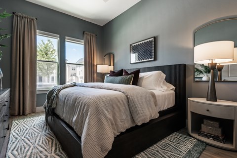 A bedroom with a large bed and a window with curtains.