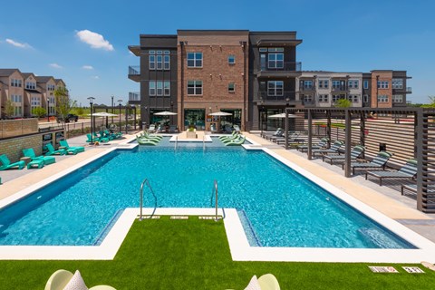 A large swimming pool in front of a multi-story apartment building.