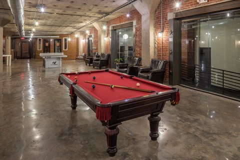 A pool table in a room with brick walls.