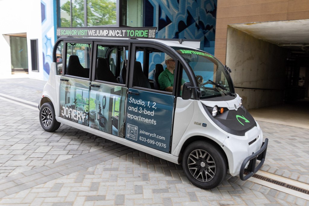 A small white car with a driver and a passenger inside.