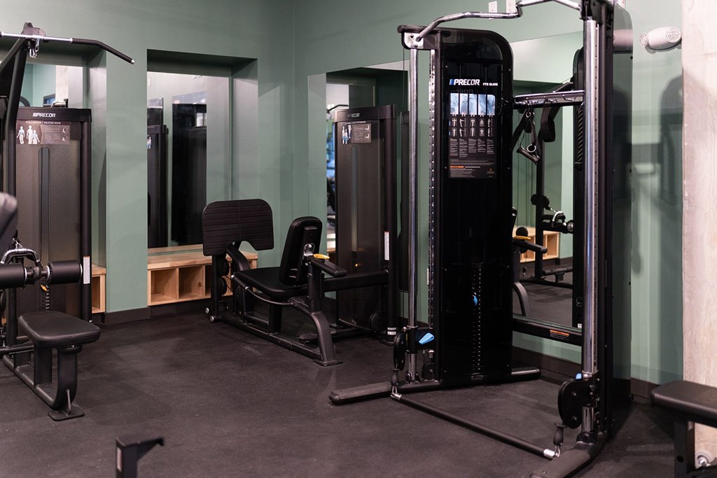 A gym with a variety of equipment including a squat rack, a leg press machine, and a bench.