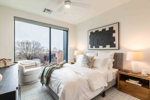A bedroom with a large bed and a chair by the window.