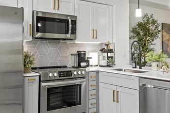 A modern kitchen with a stainless steel refrigerator, microwave, oven, and other appliances.