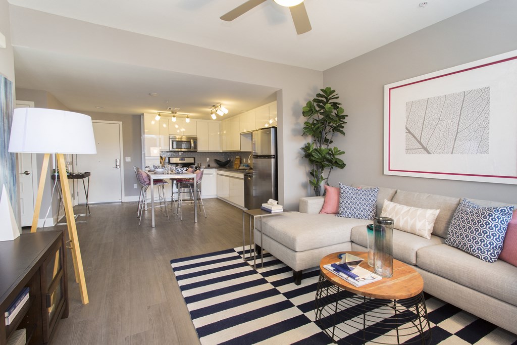 a living room with a couch coffee table and a kitchen in the background