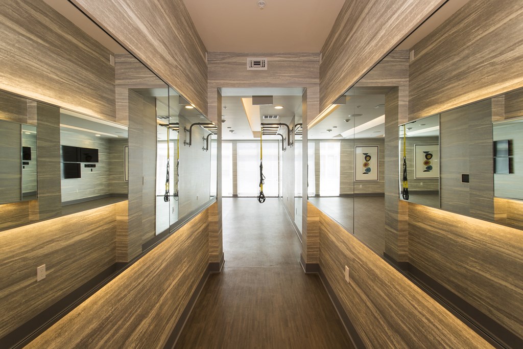 a view down the hallway of the fitness center with wooden benches and mirrors on the walls