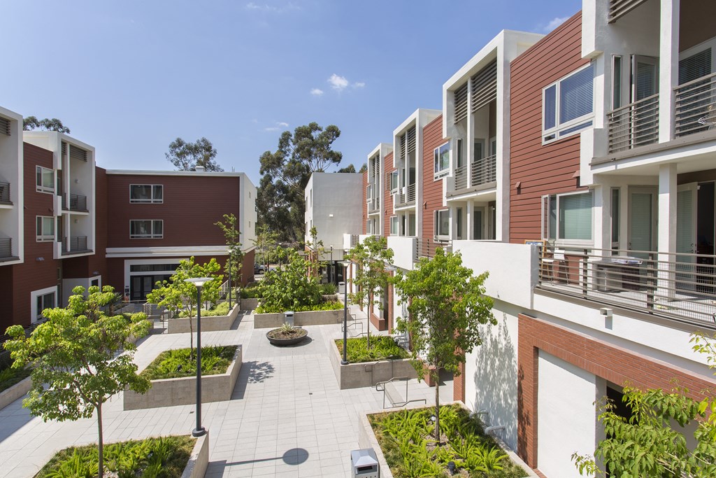 a courtyard with trees and plants in front of an apartment building