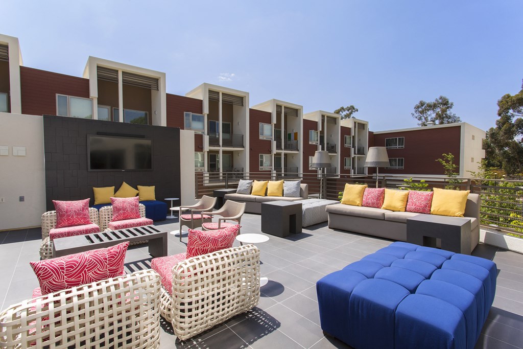 a patio with couches tables and chairs and apartments in the background