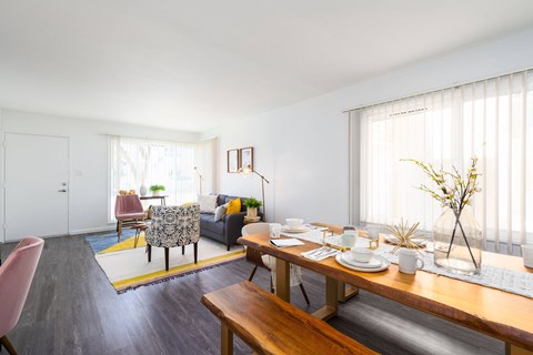 the living room and dining area with a wooden table and chairs and a couch in the background