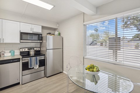A modern kitchen with a glass table and stainless steel appliances.
