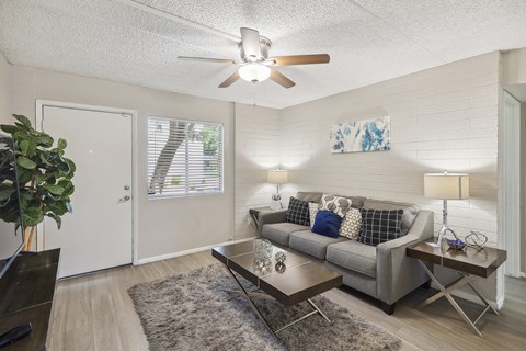 A living room with a grey couch and a ceiling fan.