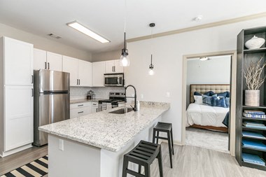 a kitchen with a breakfast bar and a bedroom in the background
