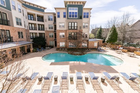 an outdoor pool with chairs and an apartment building