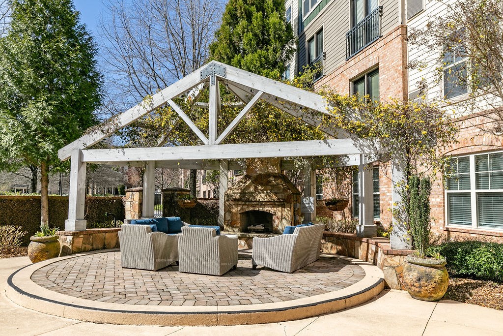 a patio with a fireplace and seating area in front of a brick building at Westmount at Ashwood, Atlanta