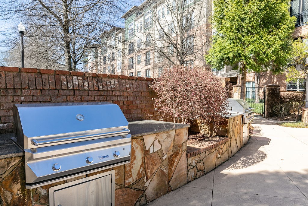 an outdoor kitchen with a grill and a tree in front of a brick wall at Westmount at Ashwood, Georgia