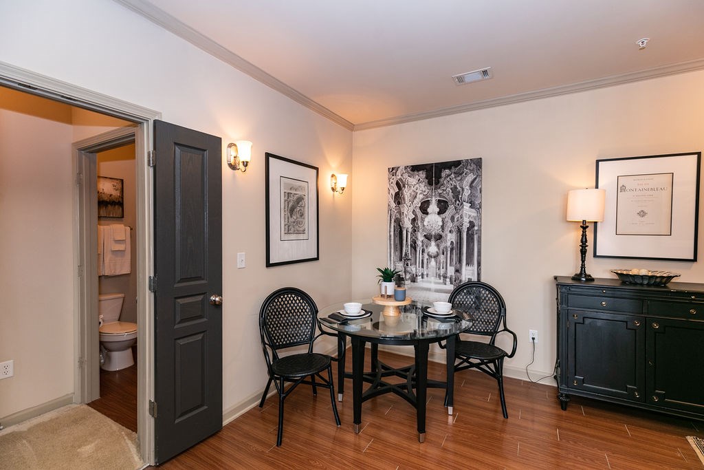 A dining room with a table set for two and a painting on the wall.
