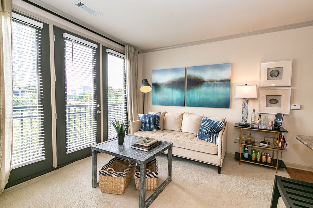 A living room with a white couch and a large painting on the wall.