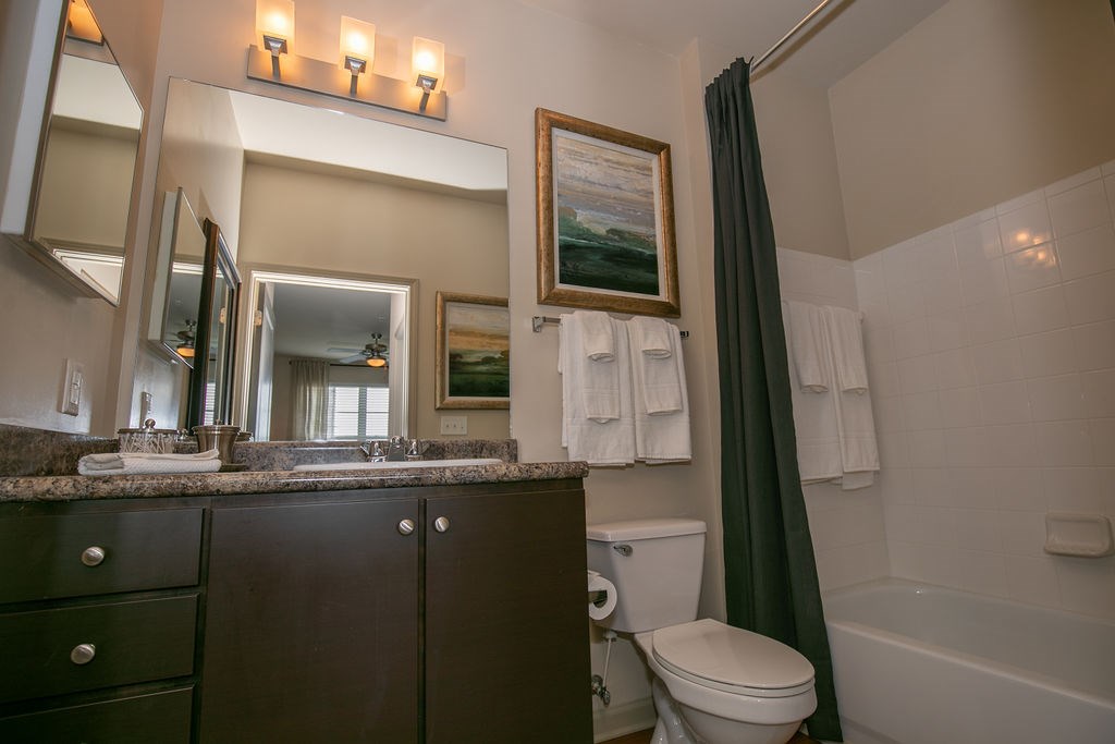 A bathroom with a toilet, sink, and a painting on the wall.