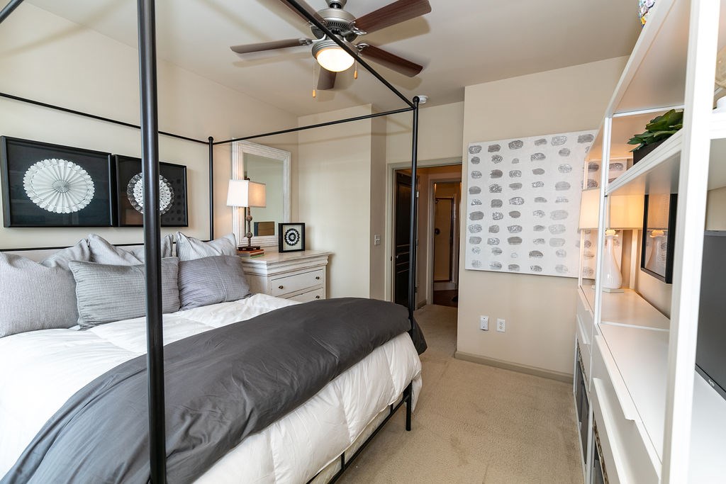 A bedroom with a four poster bed and a ceiling fan.