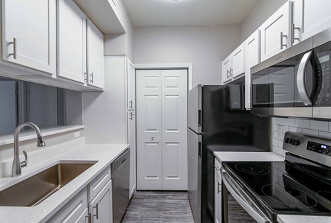 A kitchen with white cabinets and black appliances.
