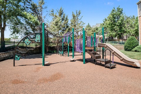 A playground with a slide, swings, and a seesaw.