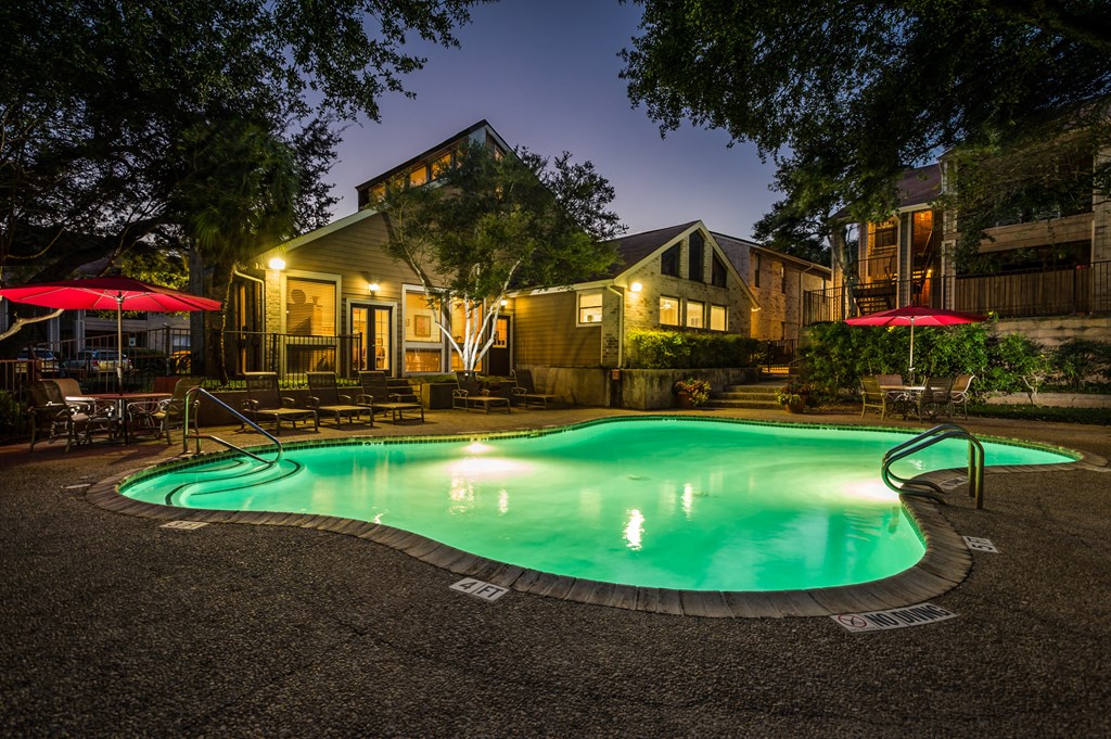 a pool at night with a house in the background