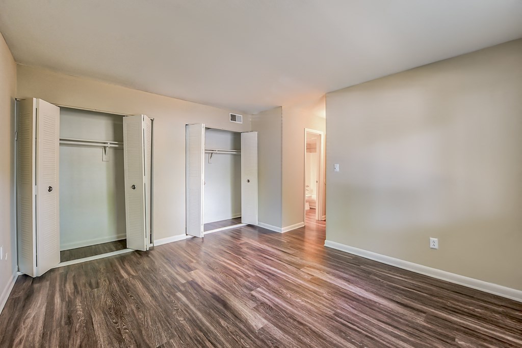 a bedroom with hardwood flooring and two closets