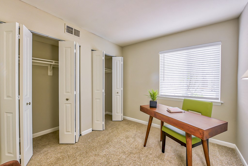 a room with a desk and chair and a closet with a window