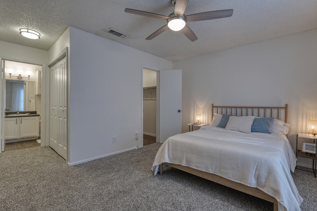 A bedroom with a bed, a dresser, and a ceiling fan.