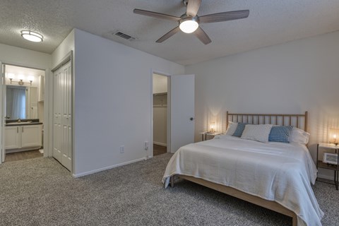 A bedroom with a bed, a dresser, and a ceiling fan.