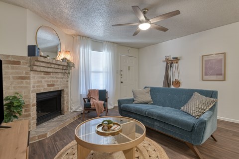 A living room with a blue couch and a fireplace.