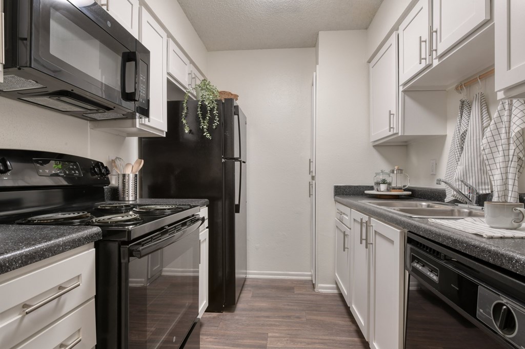 A kitchen with black appliances and white cabinets.