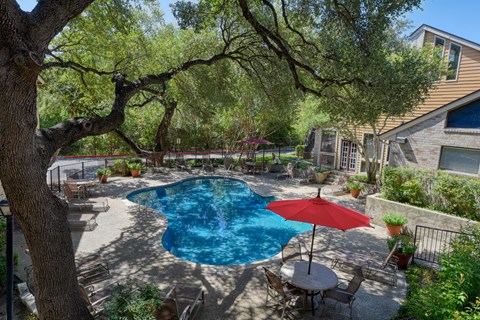 a backyard with a swimming pool and a patio with a table and chairs