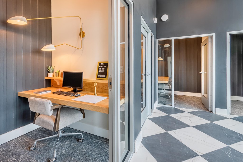 a desk with a computer in a room with a door