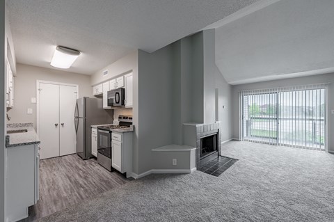 an empty living room and kitchen with a fireplace and a window