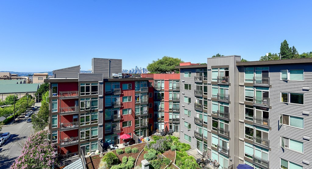 an aerial view of an apartment complex with trees and a blue sky in the background