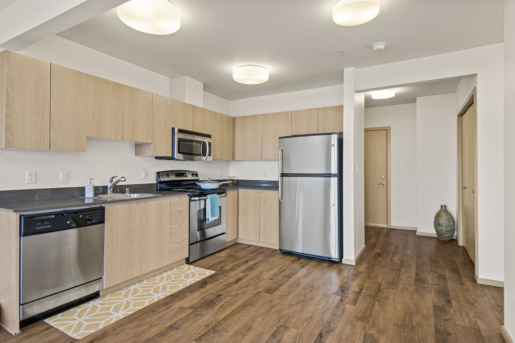 a kitchen with wood flooring and stainless steel appliances