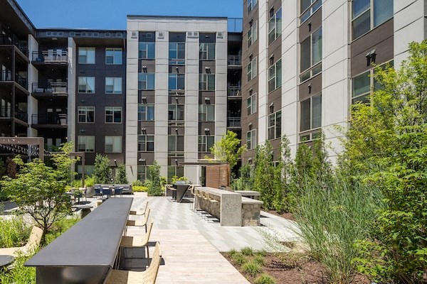 an outdoor area with benches and tables in front of an apartment building