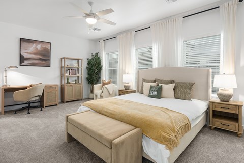 A bedroom with a large bed and a desk with a chair.