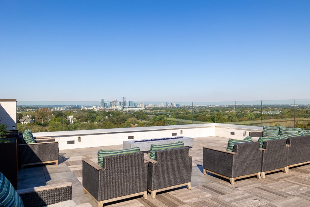 a roof deck with chairs and a view of the city