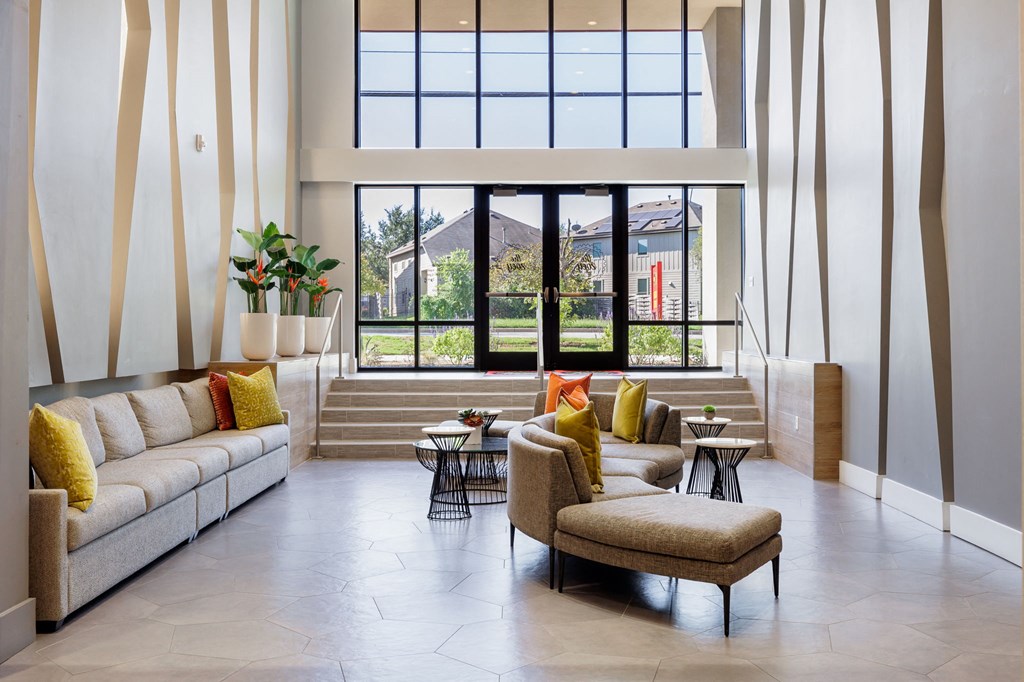 a living room with couches and chairs and large windows