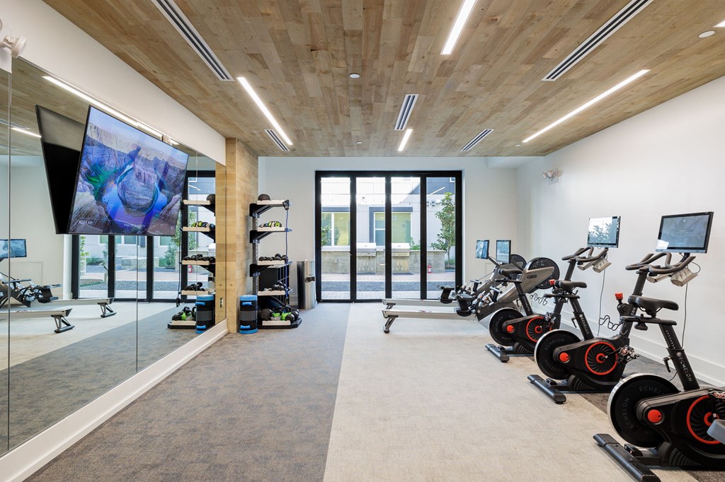 a gym with weights and cardio machines and a large glass door
