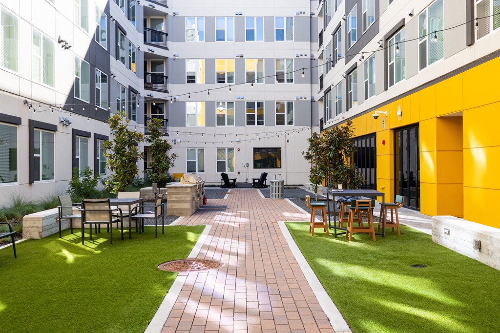 a courtyard with tables and chairs outside of an apartment building