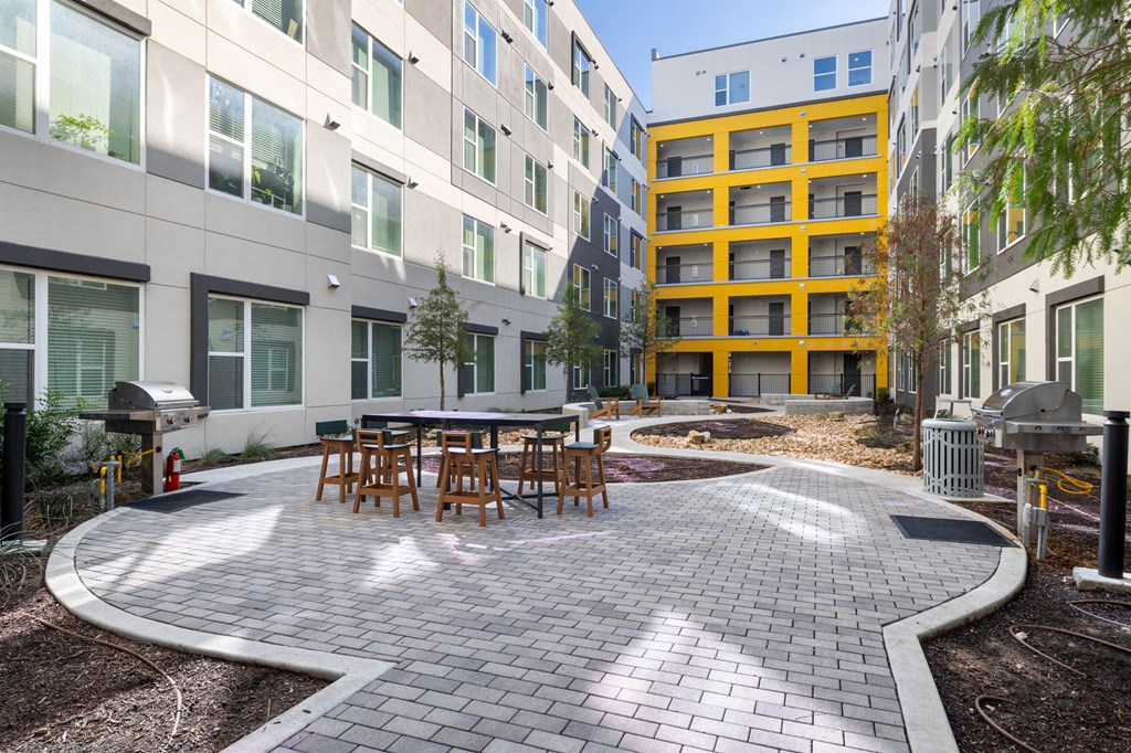 a courtyard with tables and chairs outside of an apartment building