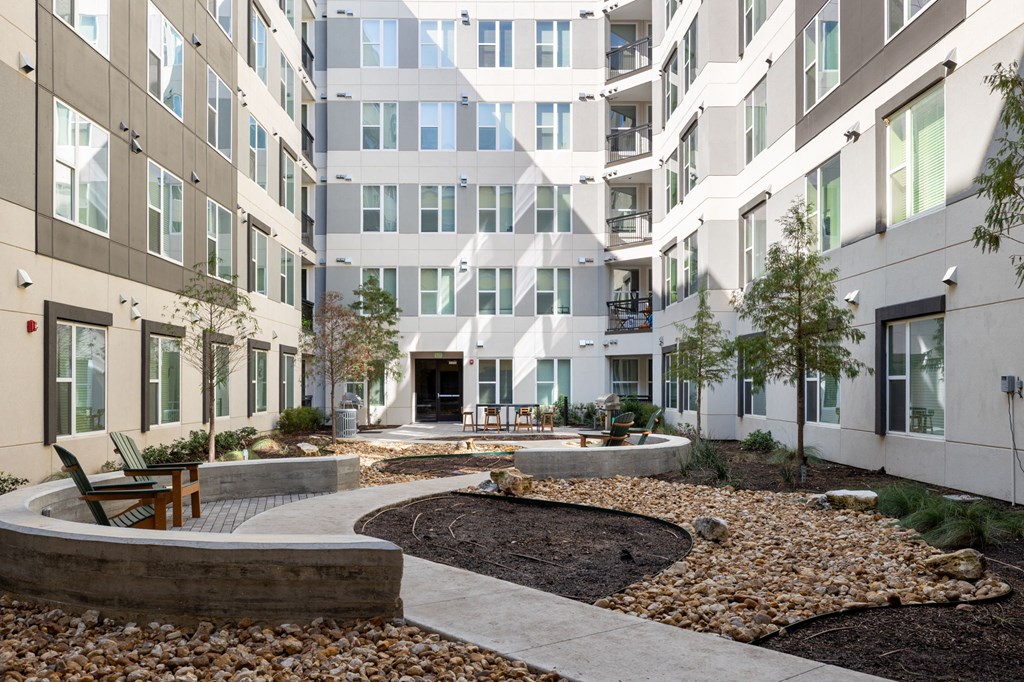 a courtyard with benches and trees in front of a building