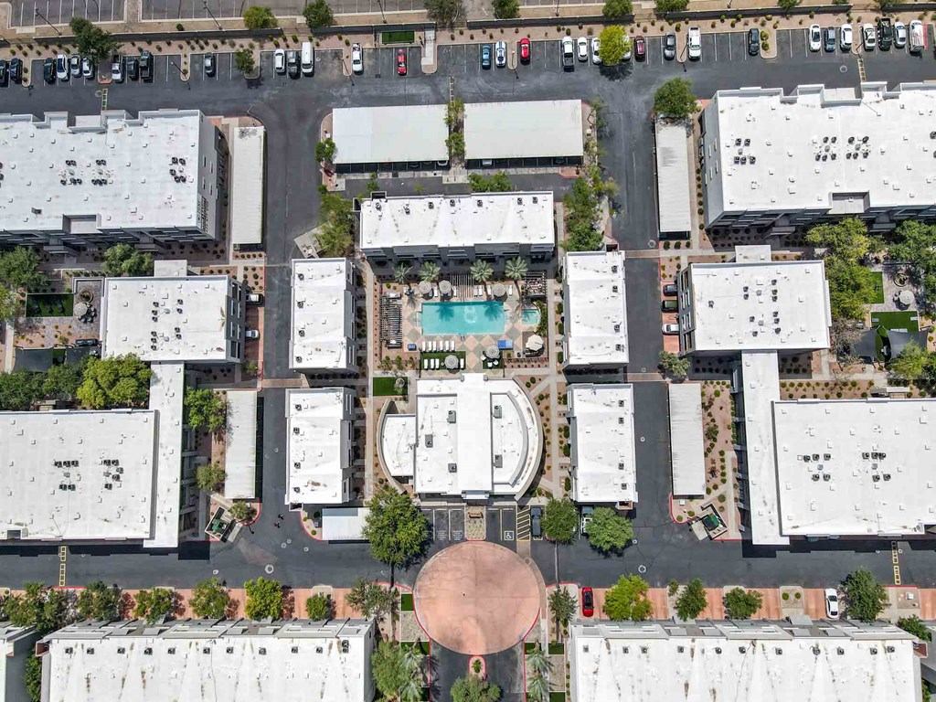 A bird's eye view of a parking lot with a roundabout and a pool in the middle of the buildings.