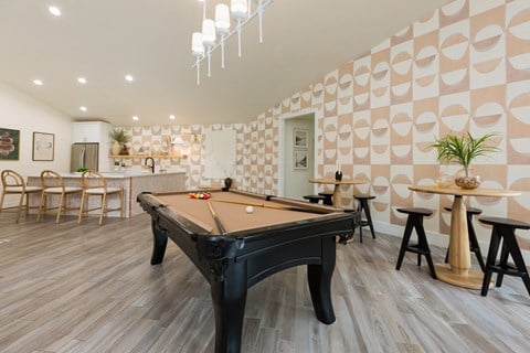 a billiards table in a clubhouse with a bar and tables